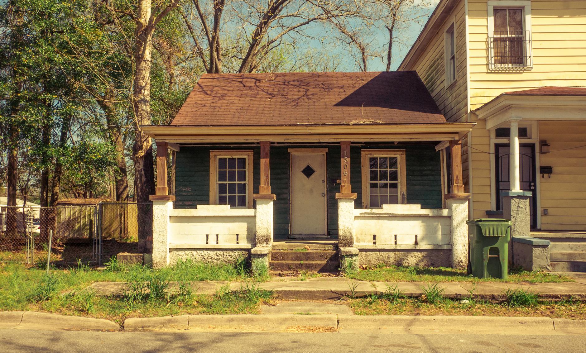 Drewniany ganek domu jednorodzinnego w słońcu na spokojnym osiedlu