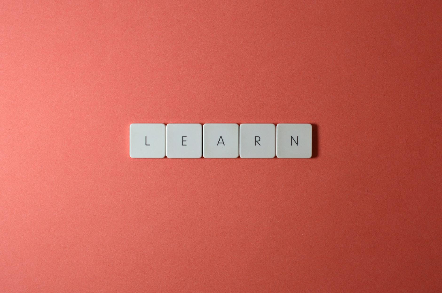 Kafle z literami układającymi się w słowo learn na koralowym tle