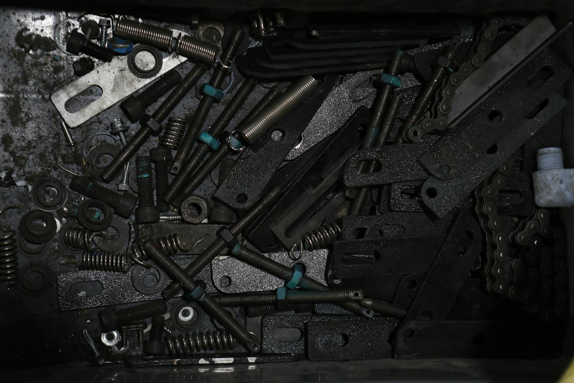 Metalowe mocowania, sprężyny i łańcuchy posegregowane w pudełku