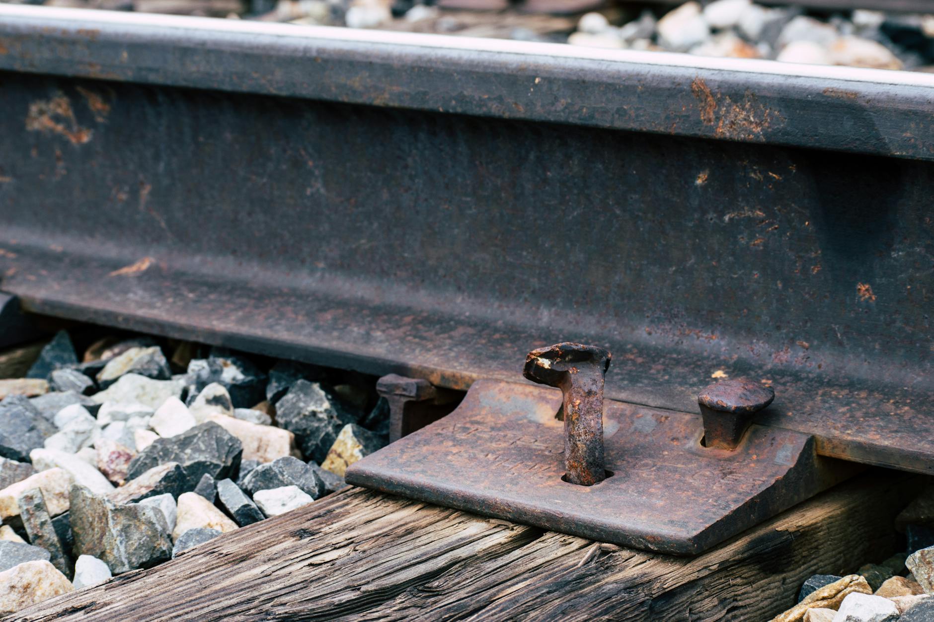 Zardzewiałe mocowania stalowych szyn kolejowych na podsypce z tłucznia