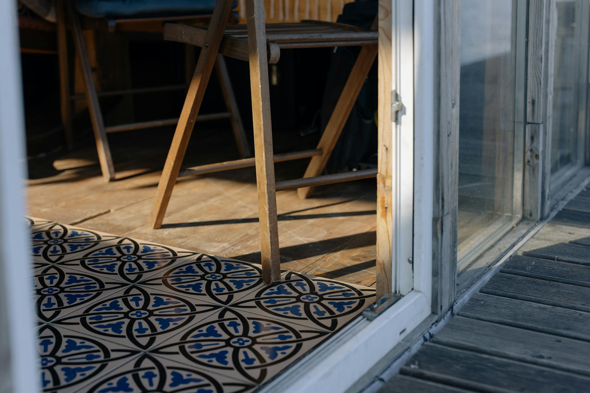 Drewniane krzesło przy dekoracyjnej podłodze z płytek w słonecznym wnętrzu Drewniane krzesło przy dekoracyjnej podłodze z płytek w słonecznym wnętrzu