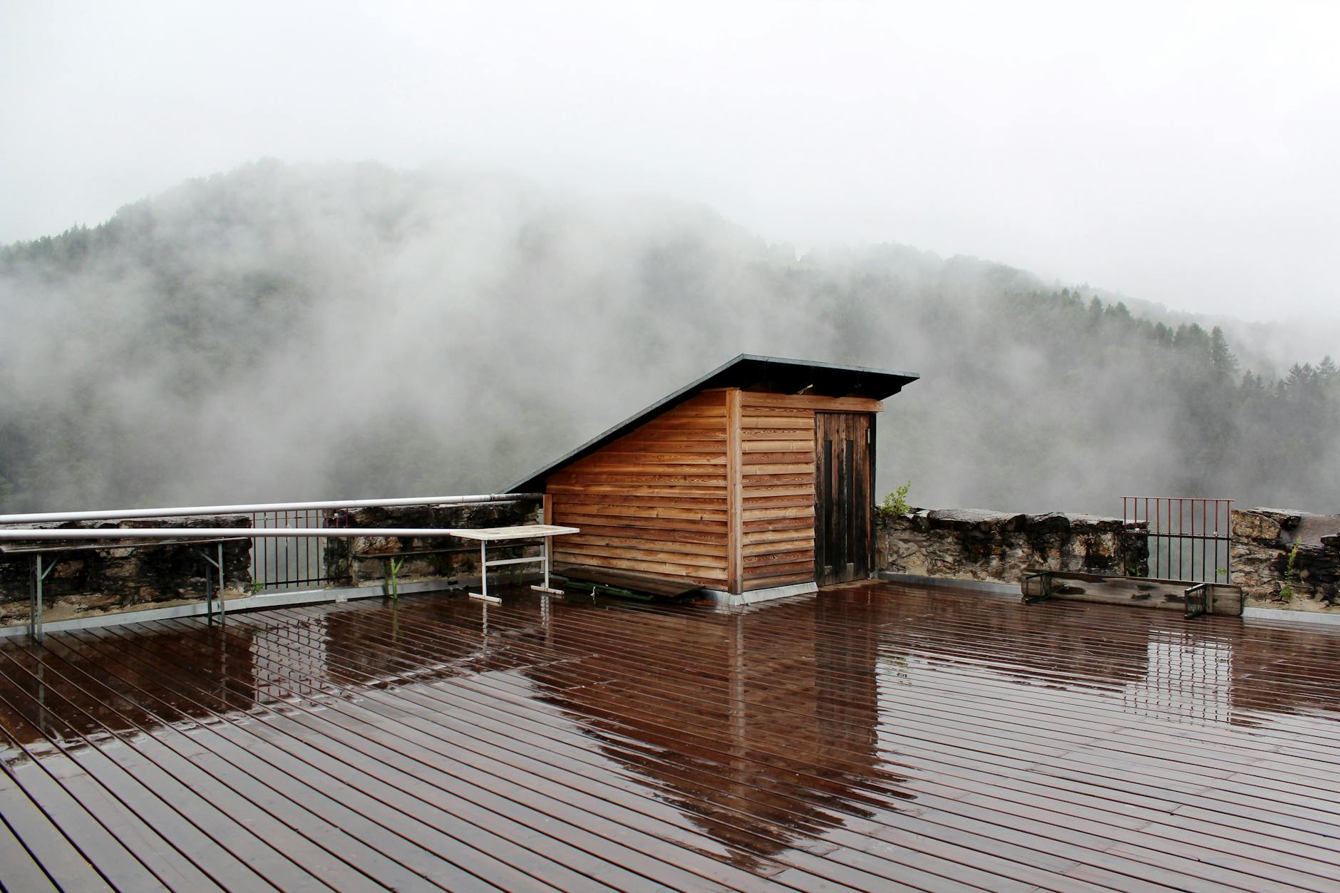 Mokra drewniana terasa z widokiem na mglisty las w górach