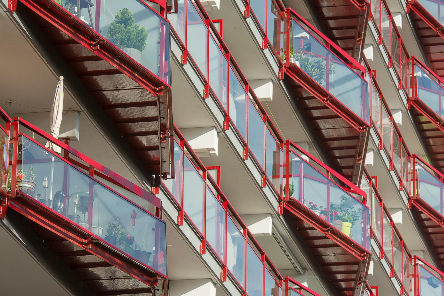 Nowoczesne balkony w bloku z czerwonymi balustradami i szkłem