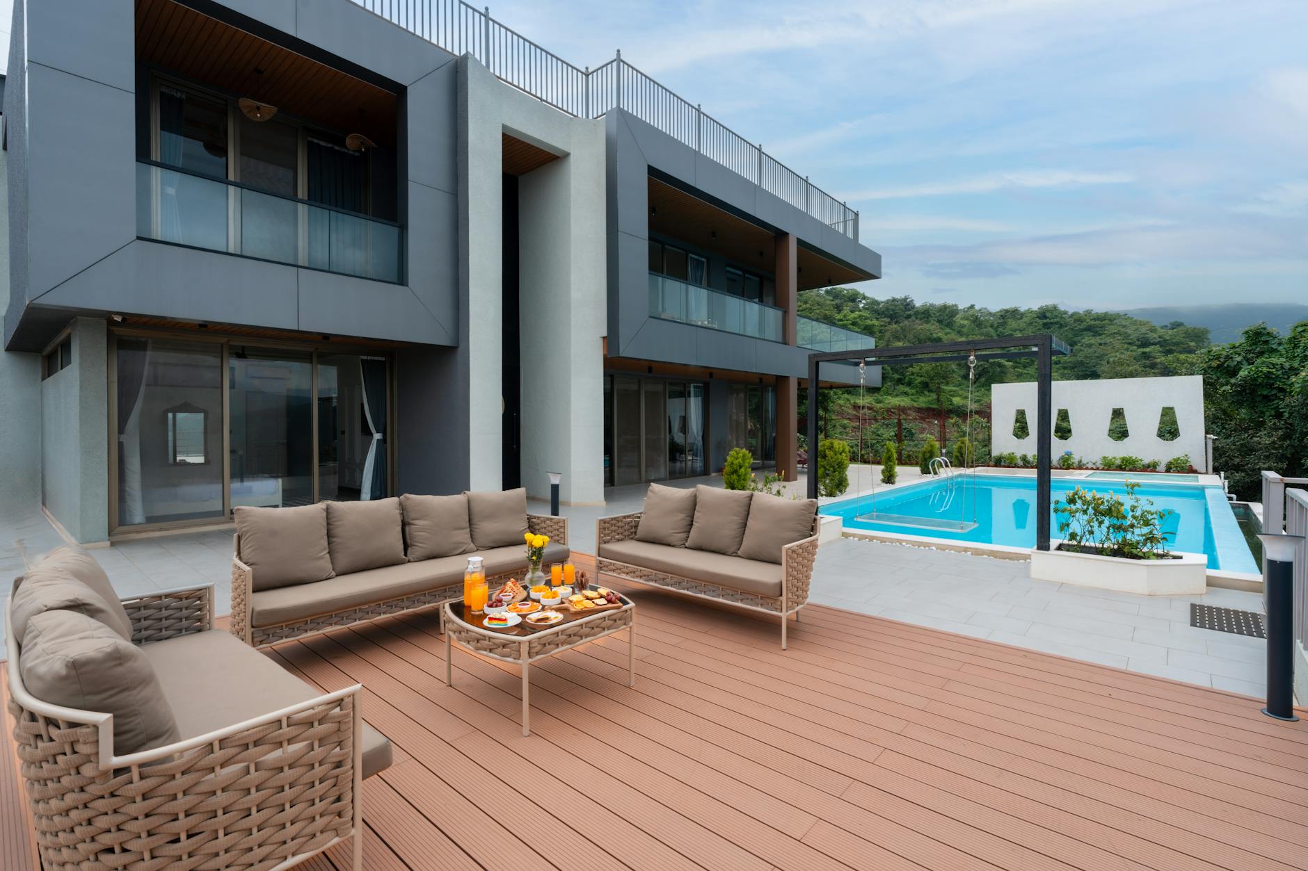 Nowoczesny taras z deskami kompozytowymi przy basenie i przeszklonym domu