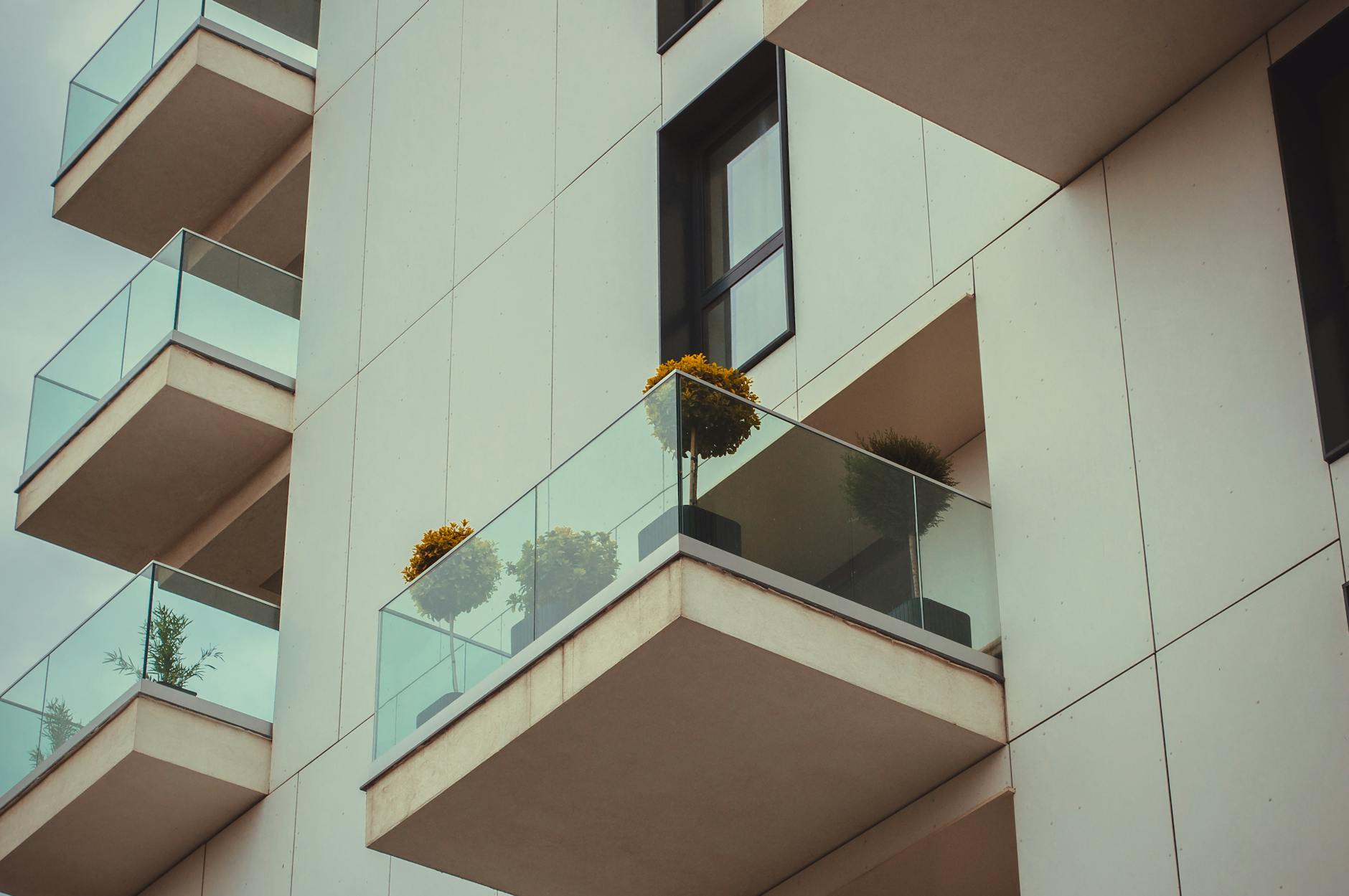 Jak dobrać klipsy i wkręty do balkonu z WPC, żeby nie skrzypiał po sezonie Szklane balkony nowoczesnego apartamentowca z roślinami w donicach