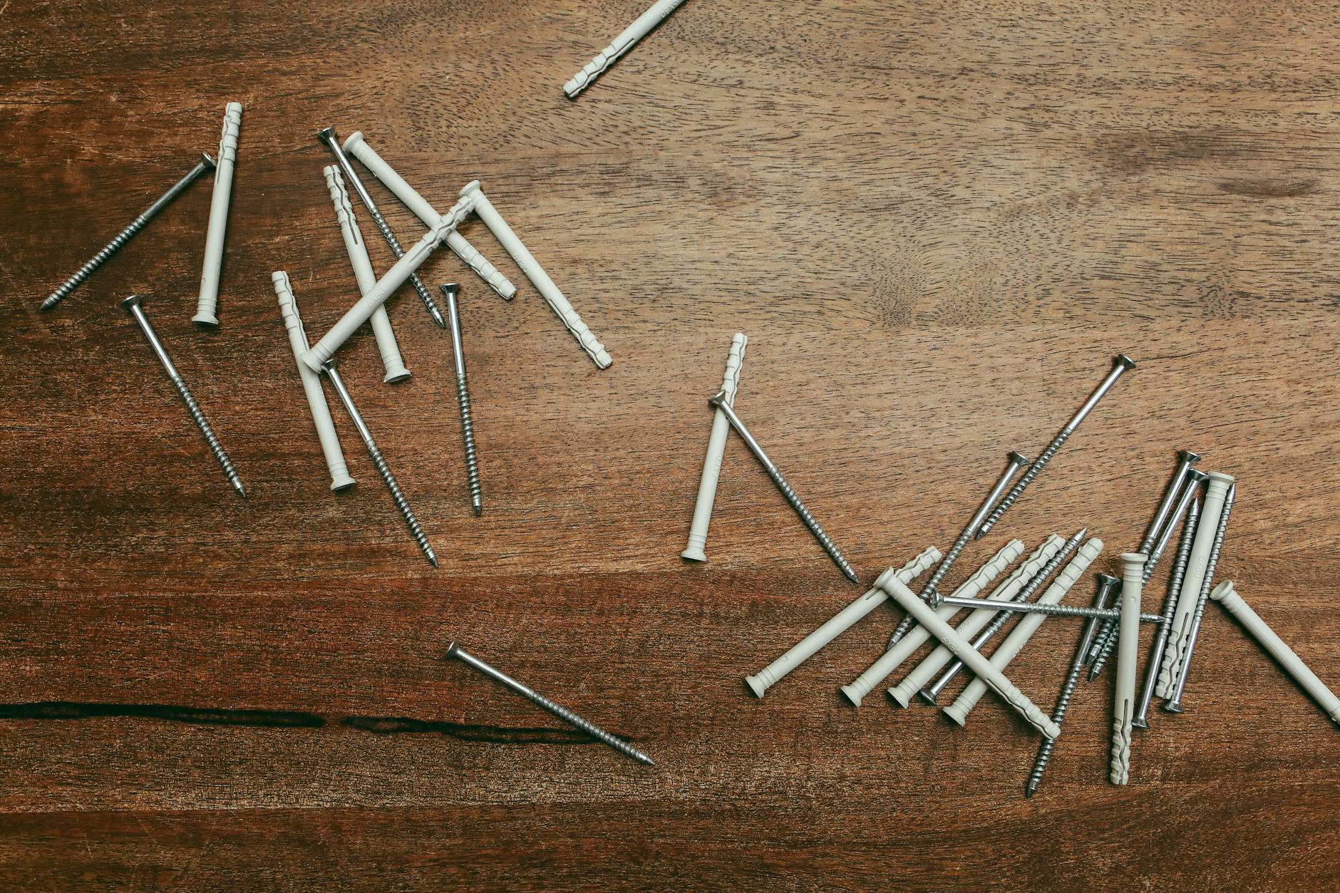 Zbliżenie na nylonowe kołki i wkręty rozrzucone na drewnianej desce