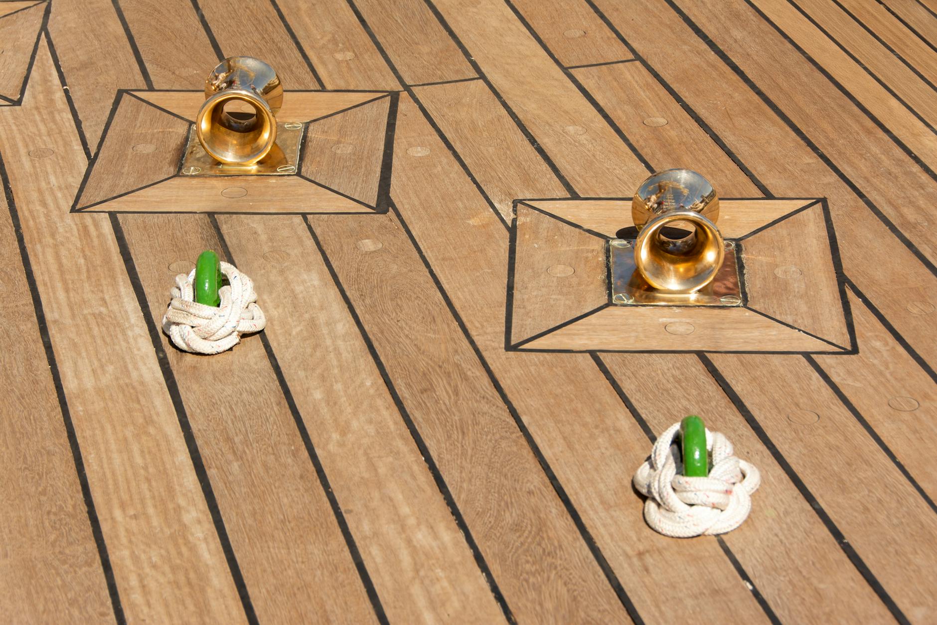 Zbliżenie pokładu jachtu z mosiężnymi knagami i przywiązaną liną