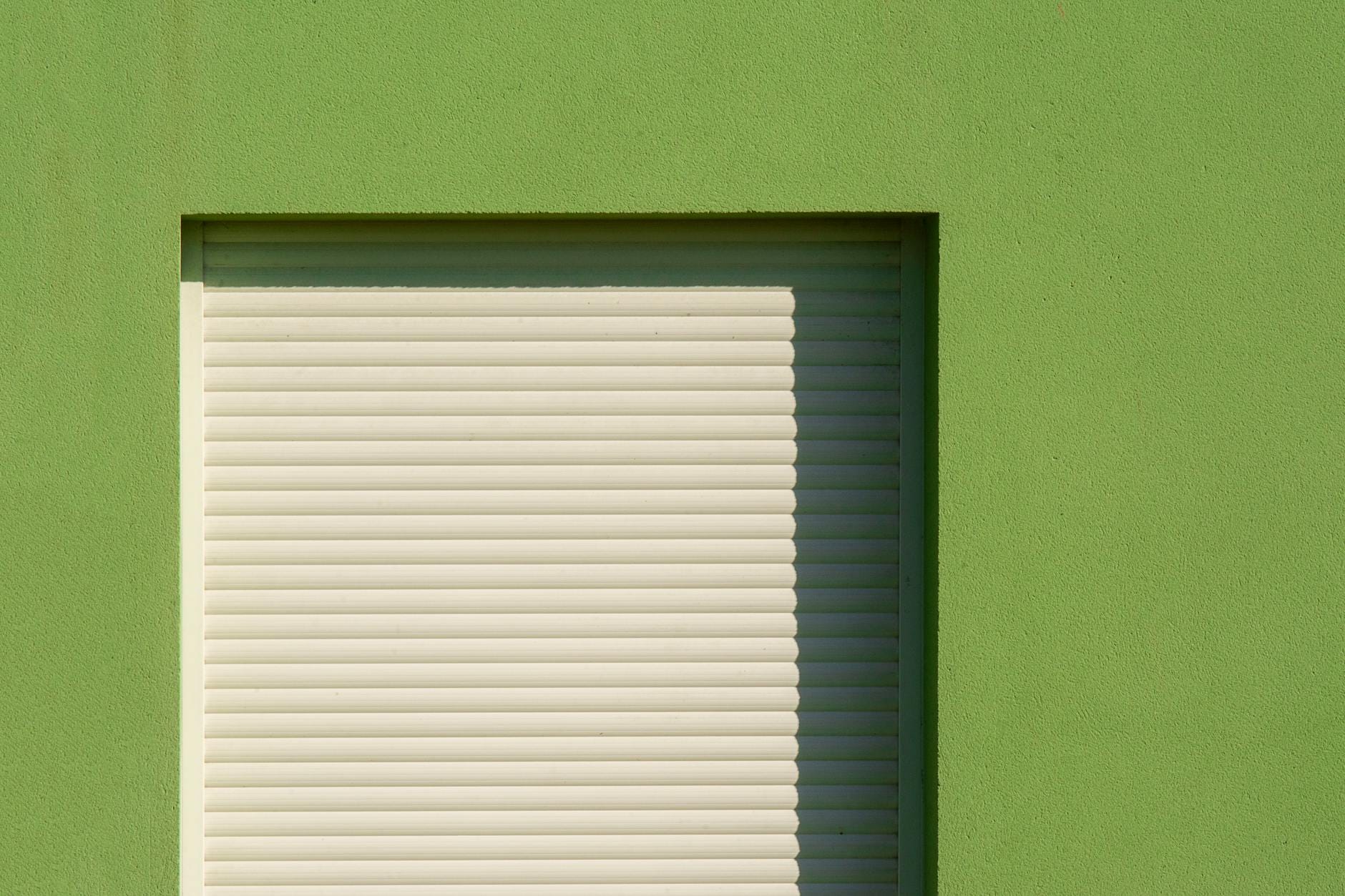 Zielona elewacja z zamkniętą żaluzją okienną w minimalistycznym stylu