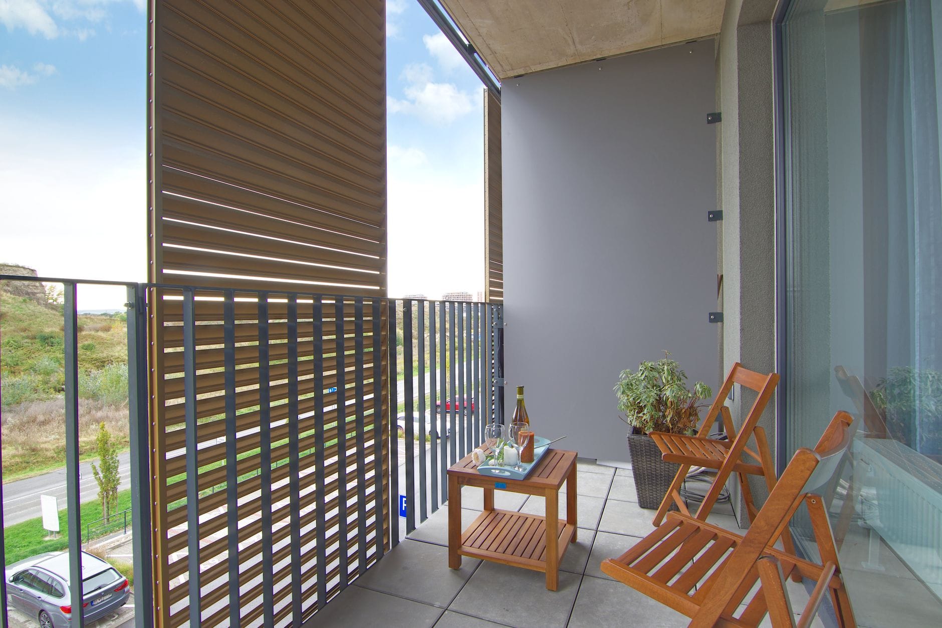 Nowoczesny balkon z drewnianymi krzesłami i stołem przy szklanej balustradzie